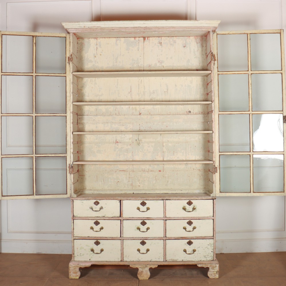 A tall Georgian painted bookcase featuring two multi-pane glazed doors above nine drawers with brass handles. View XII