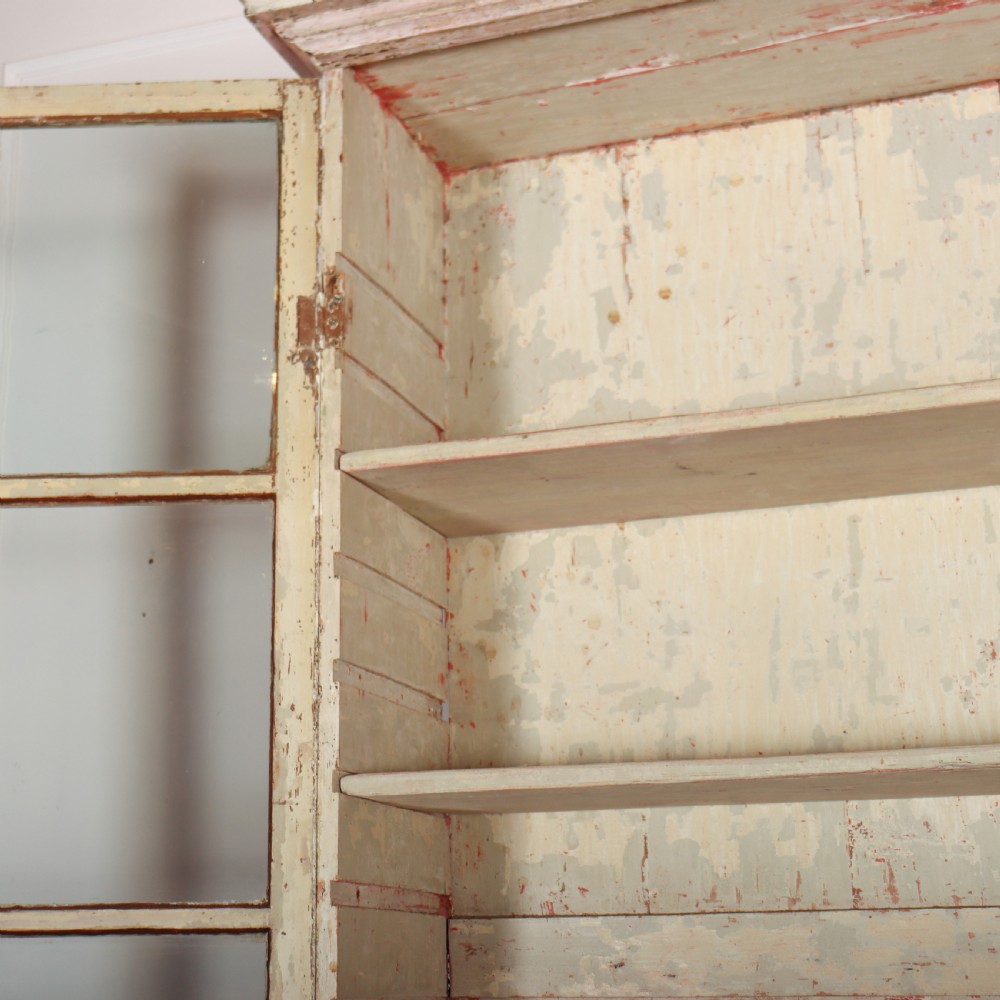 A tall Georgian painted bookcase featuring two multi-pane glazed doors above nine drawers with brass handles. View XIII