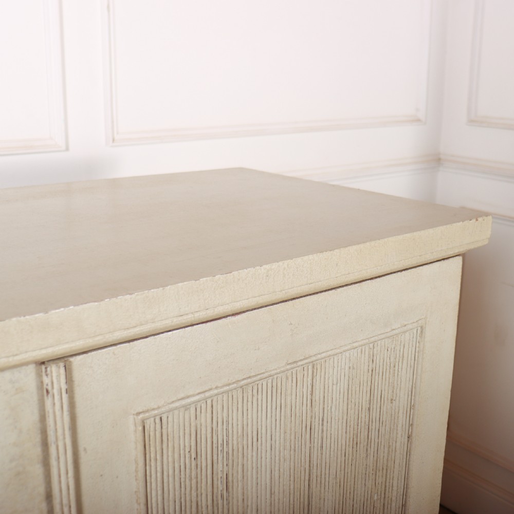 A Swedish style off-white painted wooden linen cupboard featuring three reeded panel doors with small brass knobs. View VII