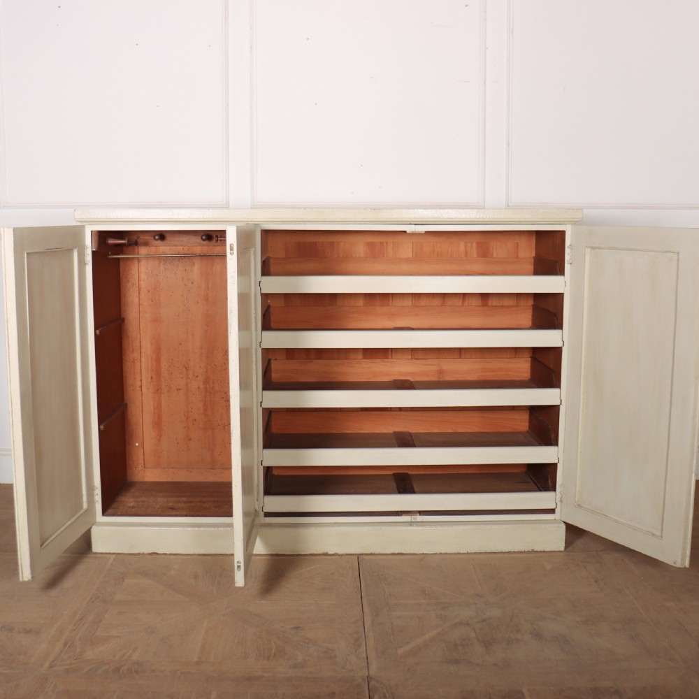 A Swedish style off-white painted wooden linen cupboard featuring three reeded panel doors with small brass knobs. View VIII