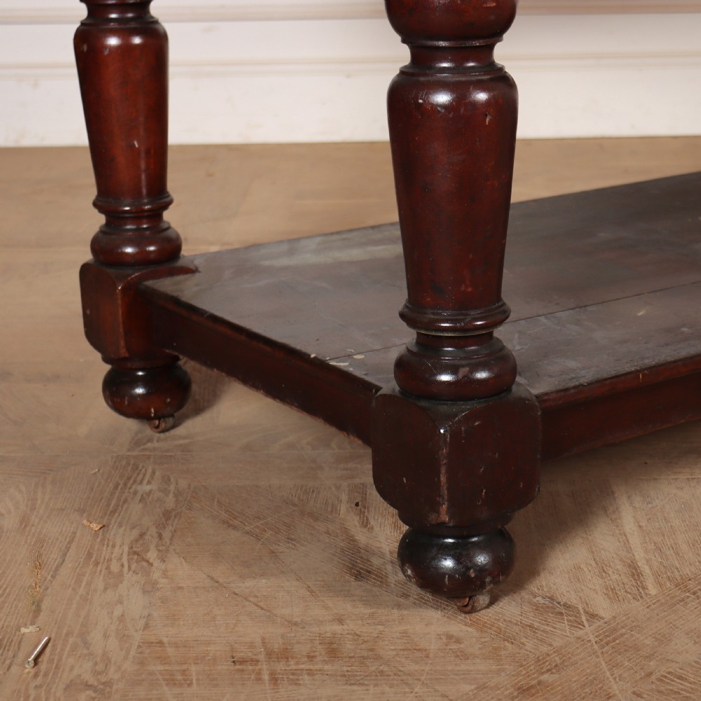A long Victorian mahogany drapers table featuring turned legs and a low potboard shelf. View V