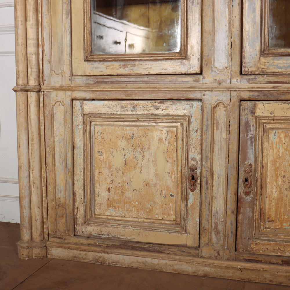 A large antique French library bookcase with four glazed upper doors, four panelled lower doors, and a distressed painted finish. View II