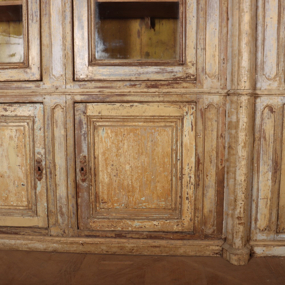 A large antique French library bookcase with four glazed upper doors, four panelled lower doors, and a distressed painted finish. View III