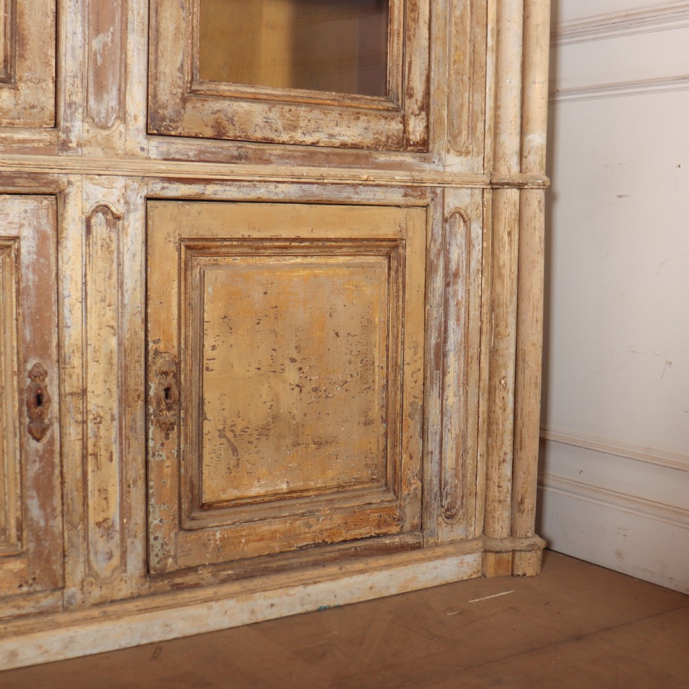 A large antique French library bookcase with four glazed upper doors, four panelled lower doors, and a distressed painted finish. View V