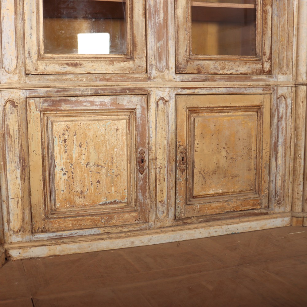 A large antique French library bookcase with four glazed upper doors, four panelled lower doors, and a distressed painted finish. View VI