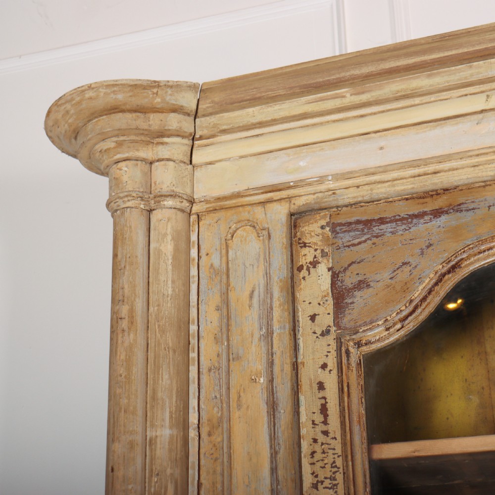 A large antique French library bookcase with four glazed upper doors, four panelled lower doors, and a distressed painted finish. View IX