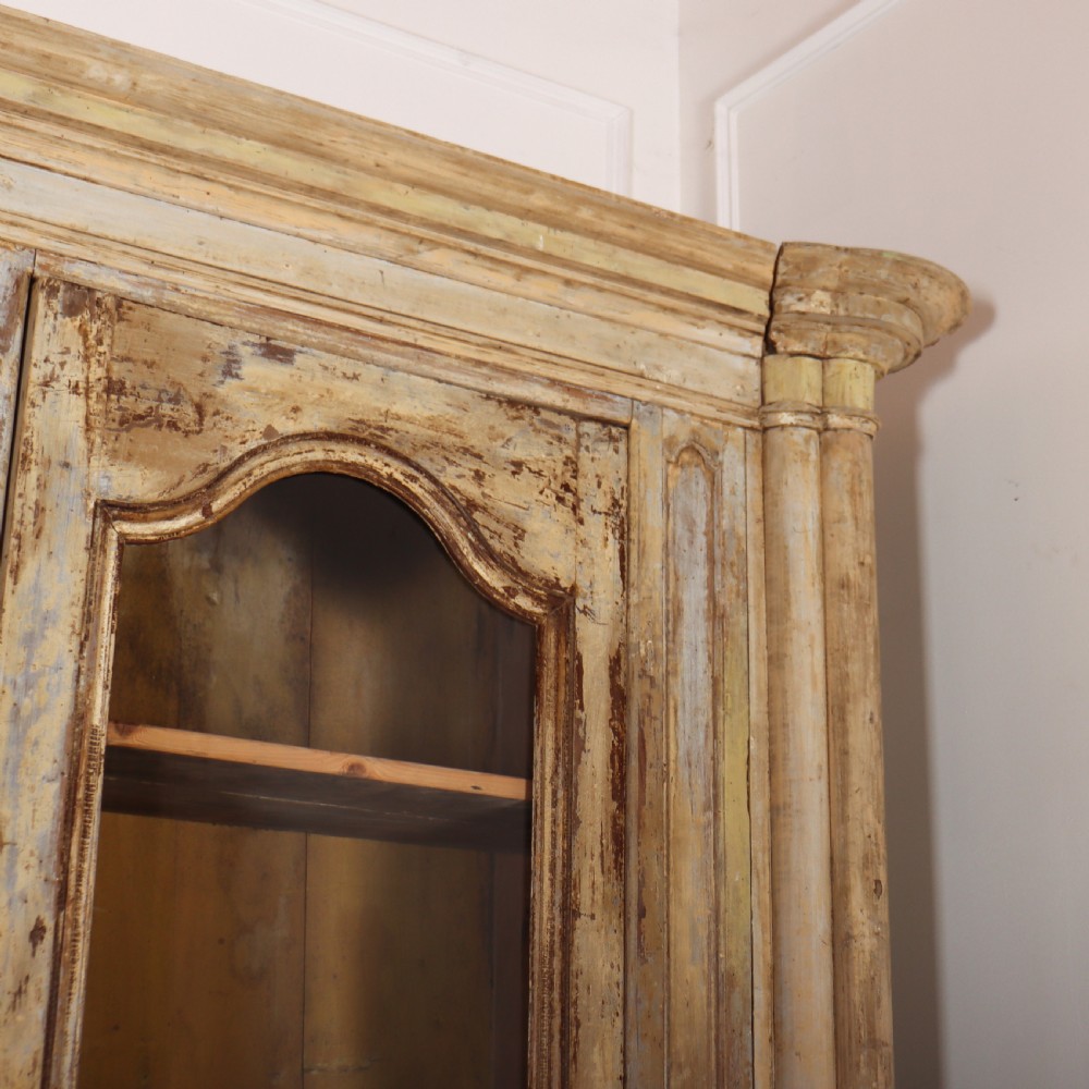 A large antique French library bookcase with four glazed upper doors, four panelled lower doors, and a distressed painted finish. View XI