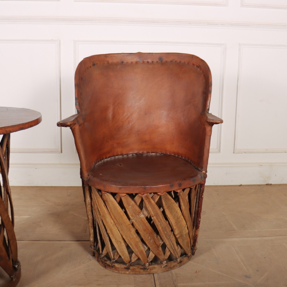 A rustic furniture set featuring a curved tub armchair and a matching round side table, both constructed with diagonally woven willow slat bases and tan leather tops. View II