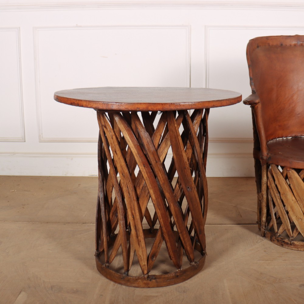 A rustic furniture set featuring a curved tub armchair and a matching round side table, both constructed with diagonally woven willow slat bases and tan leather tops. View III