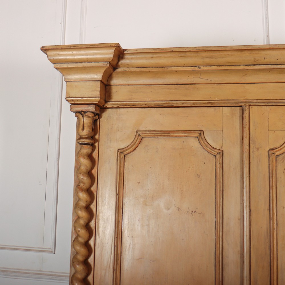 A large four-door cream painted wooden wardrobe featuring carved barley twist pilasters and shaped door panels. View II