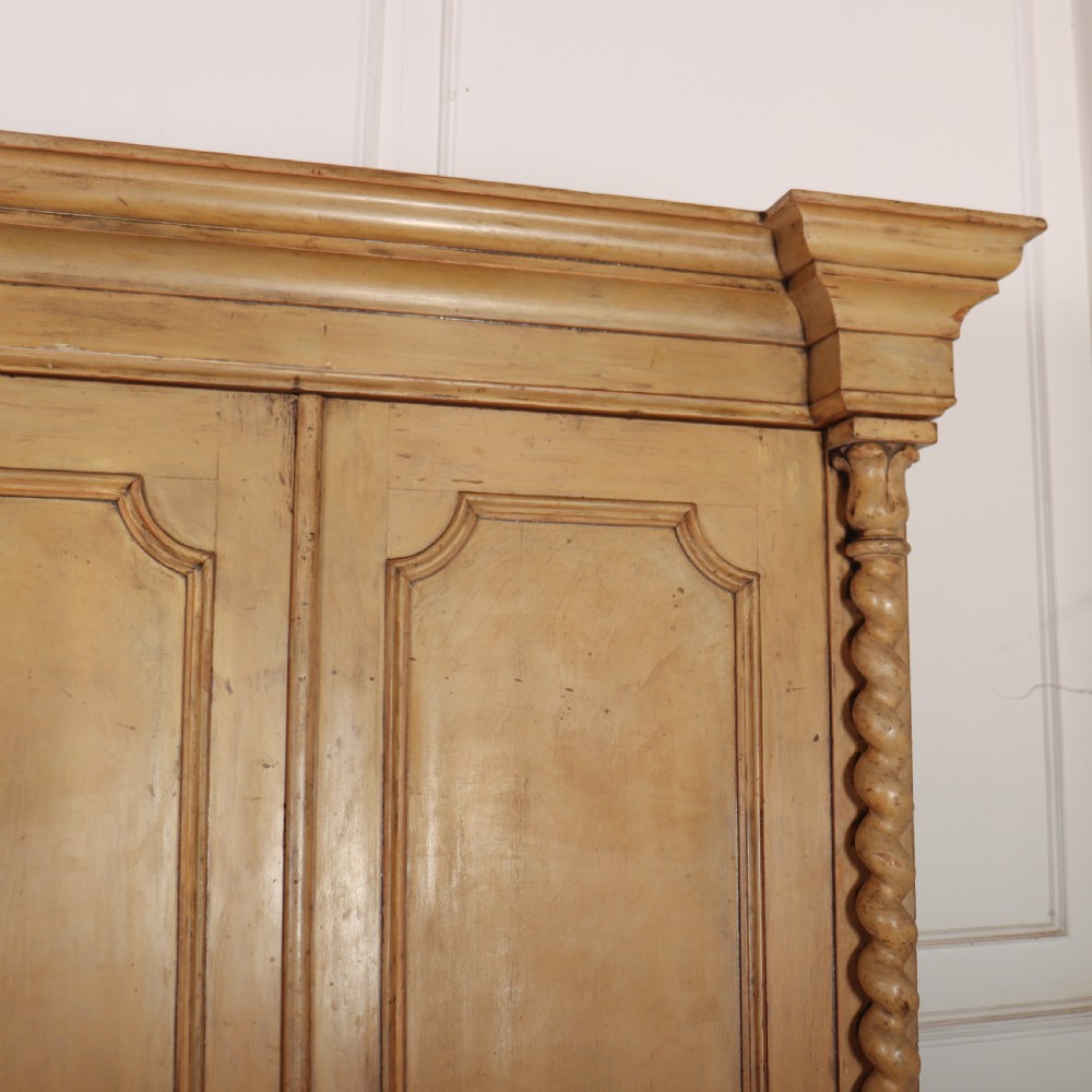 A large four-door cream painted wooden wardrobe featuring carved barley twist pilasters and shaped door panels. View V