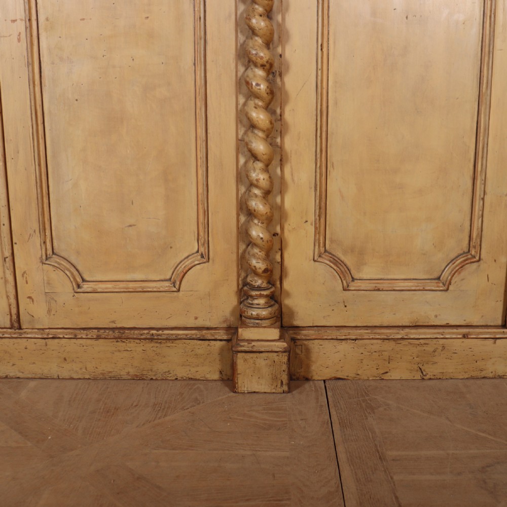 A large four-door cream painted wooden wardrobe featuring carved barley twist pilasters and shaped door panels. View VI