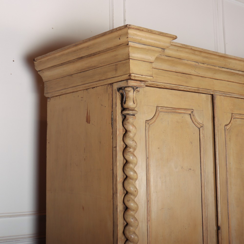 A large four-door cream painted wooden wardrobe featuring carved barley twist pilasters and shaped door panels. View VIII