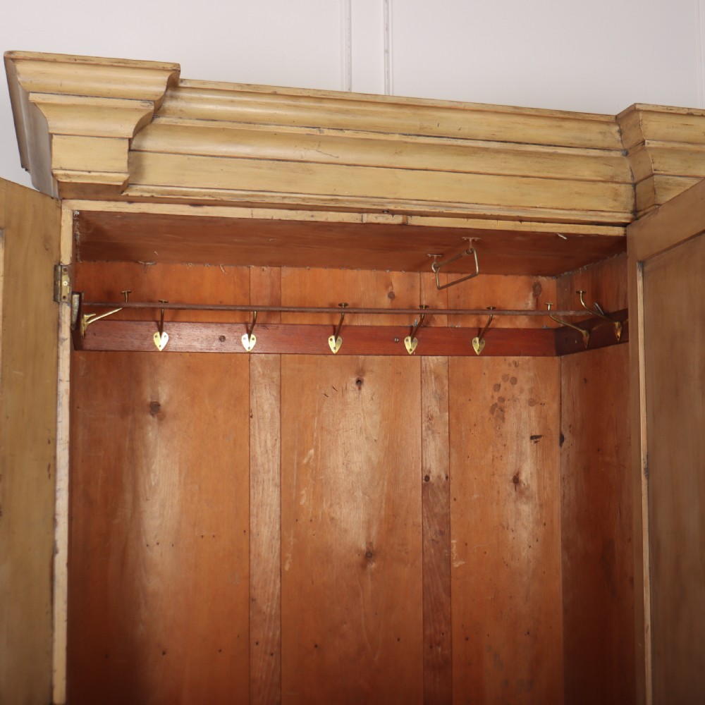 A large four-door cream painted wooden wardrobe featuring carved barley twist pilasters and shaped door panels. View XI