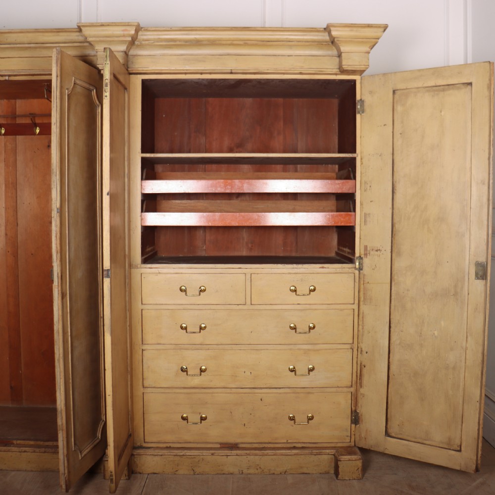 A large four-door cream painted wooden wardrobe featuring carved barley twist pilasters and shaped door panels. View XII