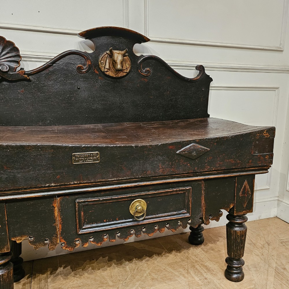 A 19th-century French ebonised timber butchers block featuring a carved splashback with brass bull head mounts, turned legs, and lower drawers. View III