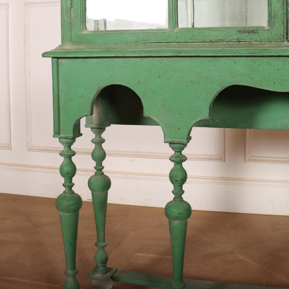 A 19th-century green painted display cabinet featuring twin arched glazed doors, a scalloped apron, and six turned legs joined by a shaped stretcher. View VI