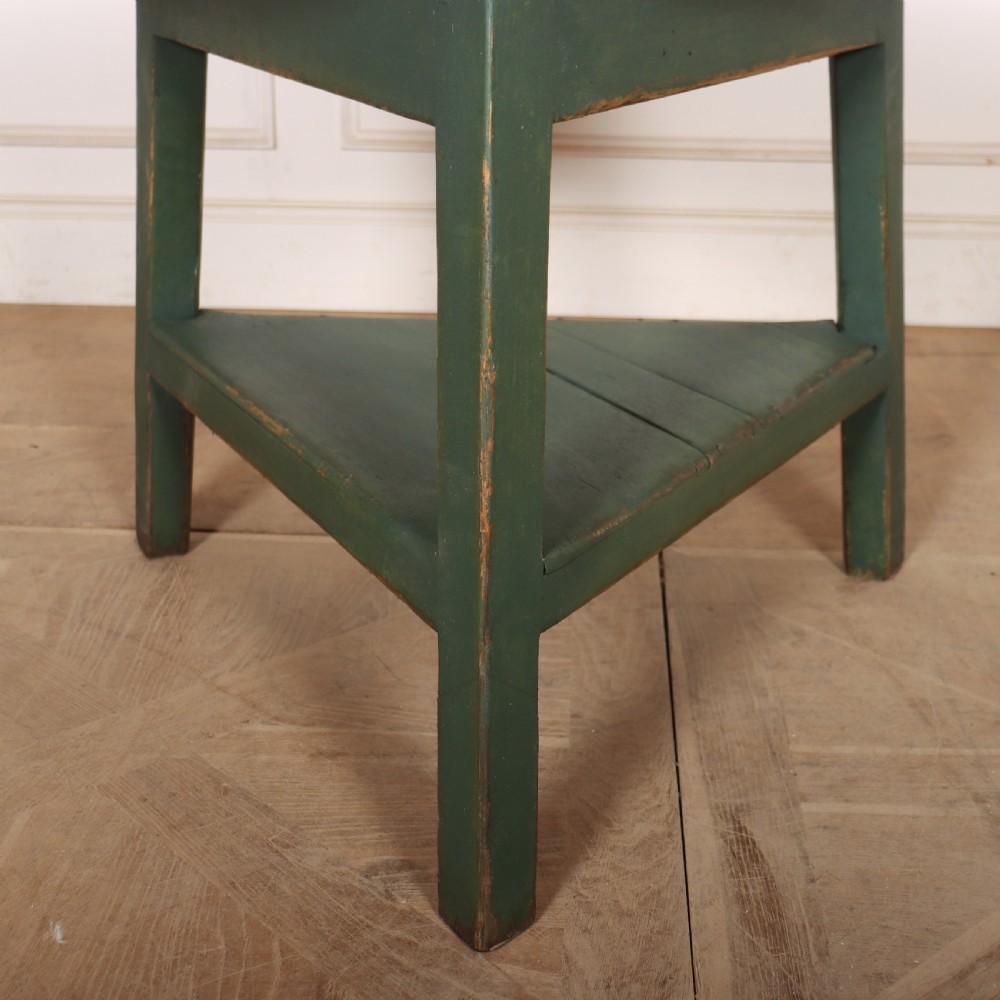 A circular wooden cricket table featuring an unpainted pale timber top mounted on a dark green painted three-legged base with a lower triangular shelf. View II