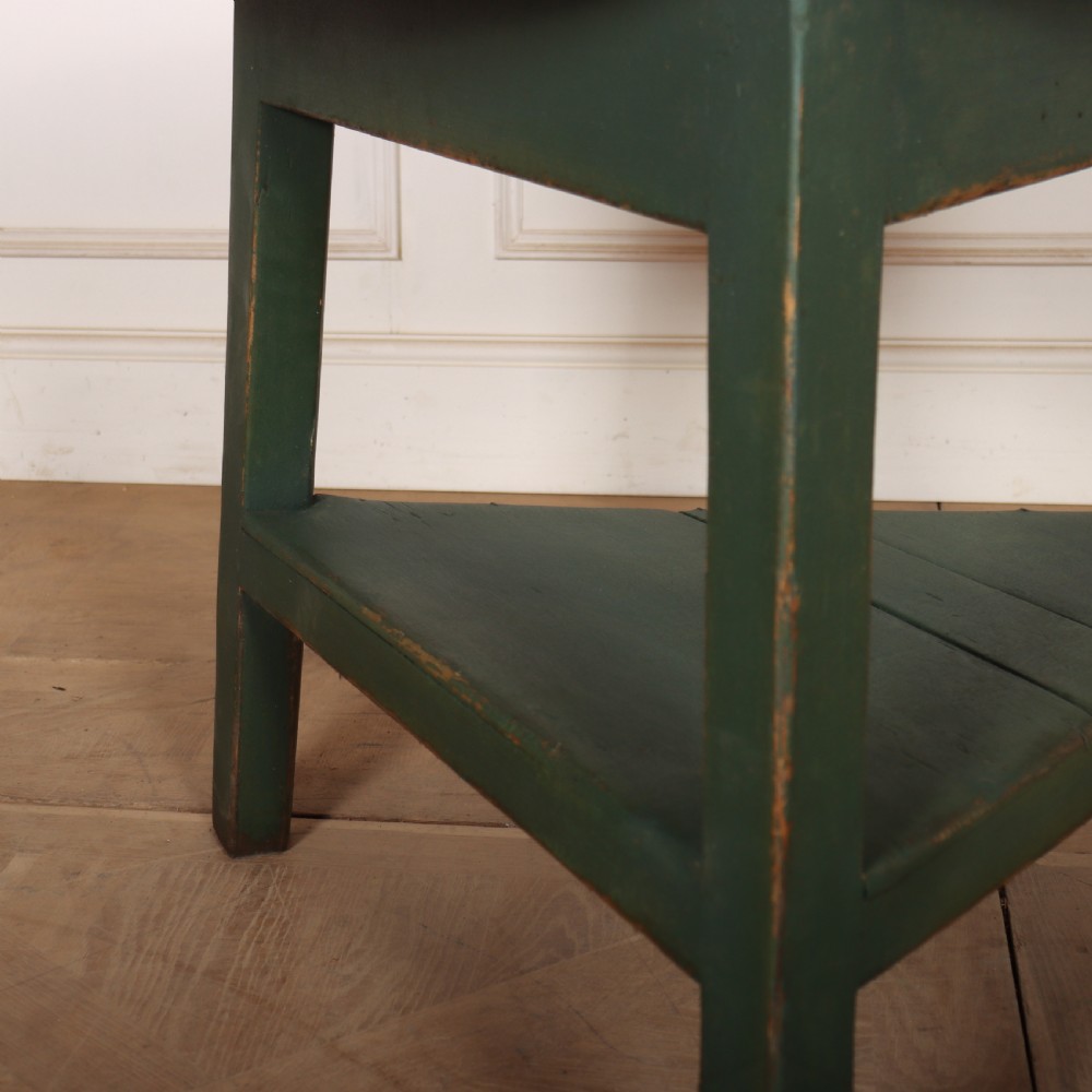 A circular wooden cricket table featuring an unpainted pale timber top mounted on a dark green painted three-legged base with a lower triangular shelf. View IV