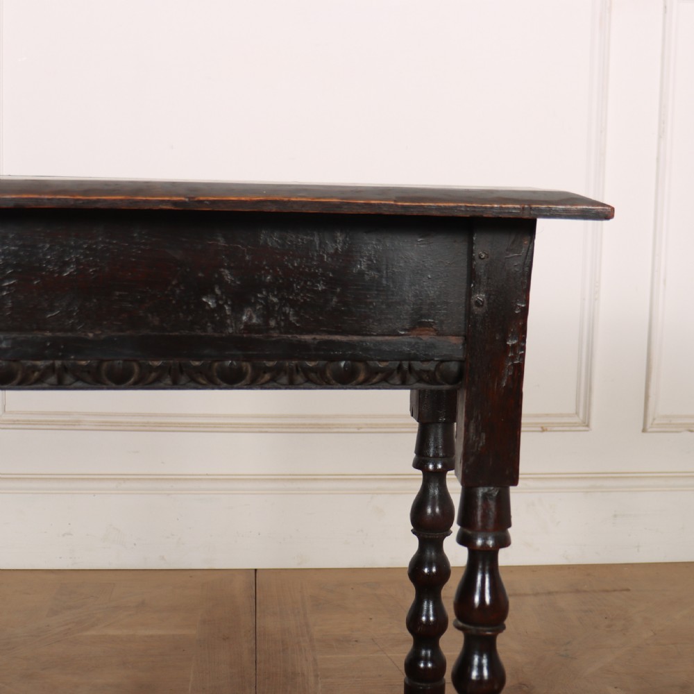 An 18th-century dark oak side table featuring turned legs, lower box stretchers, and a carved apron frieze. View II