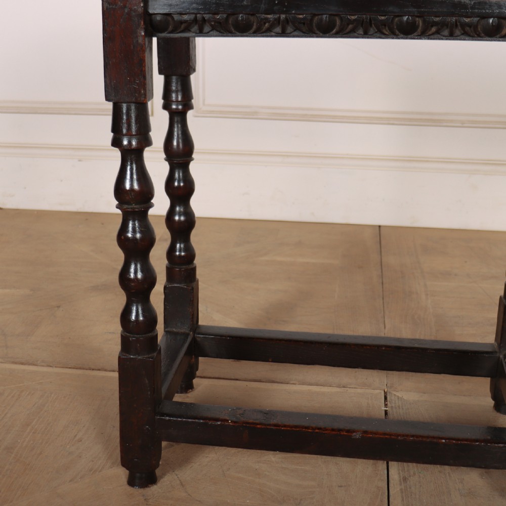 An 18th-century dark oak side table featuring turned legs, lower box stretchers, and a carved apron frieze. View III