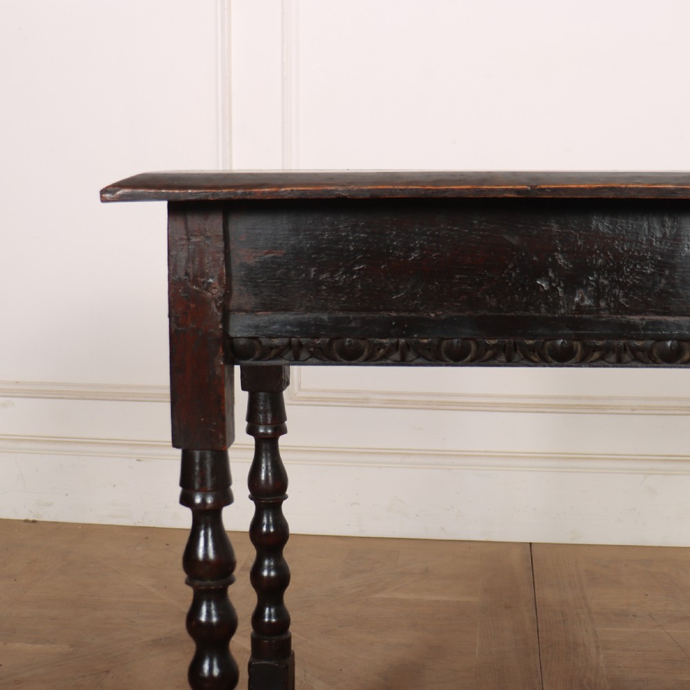 An 18th-century dark oak side table featuring turned legs, lower box stretchers, and a carved apron frieze. View IV
