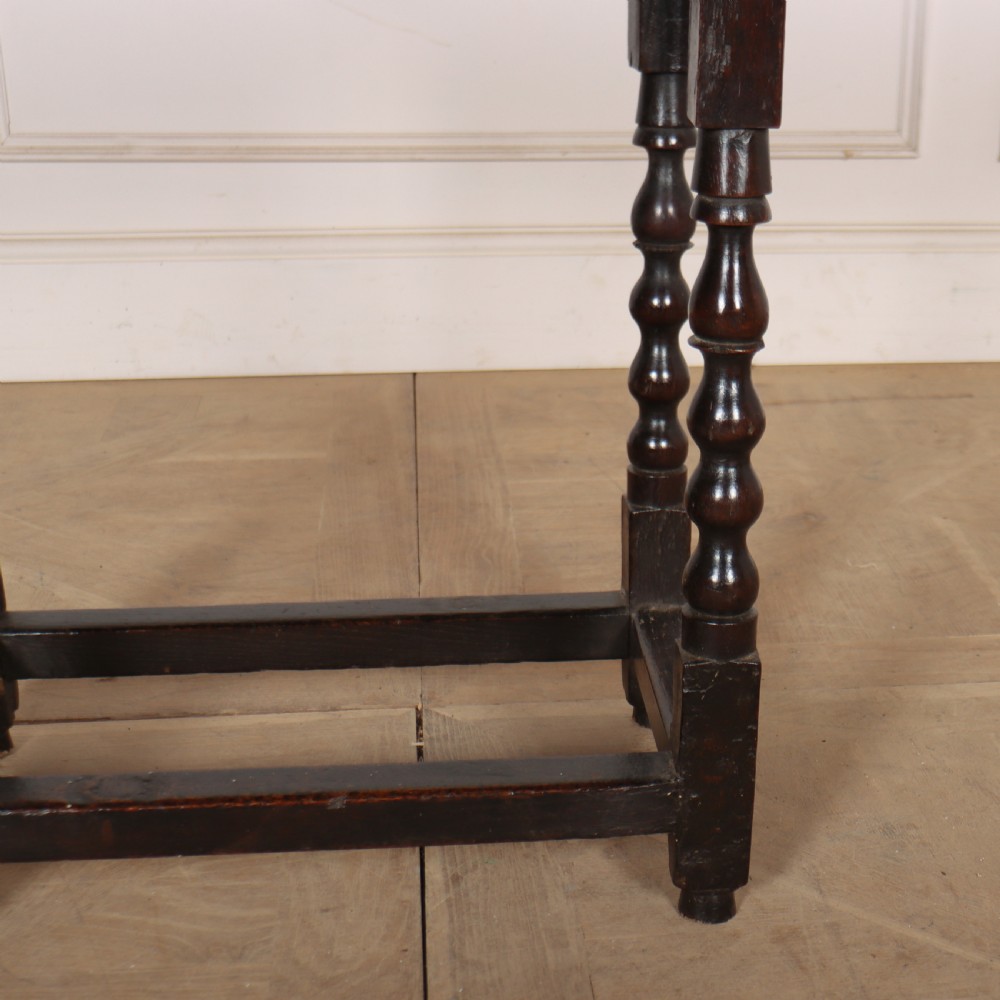 An 18th-century dark oak side table featuring turned legs, lower box stretchers, and a carved apron frieze. View V