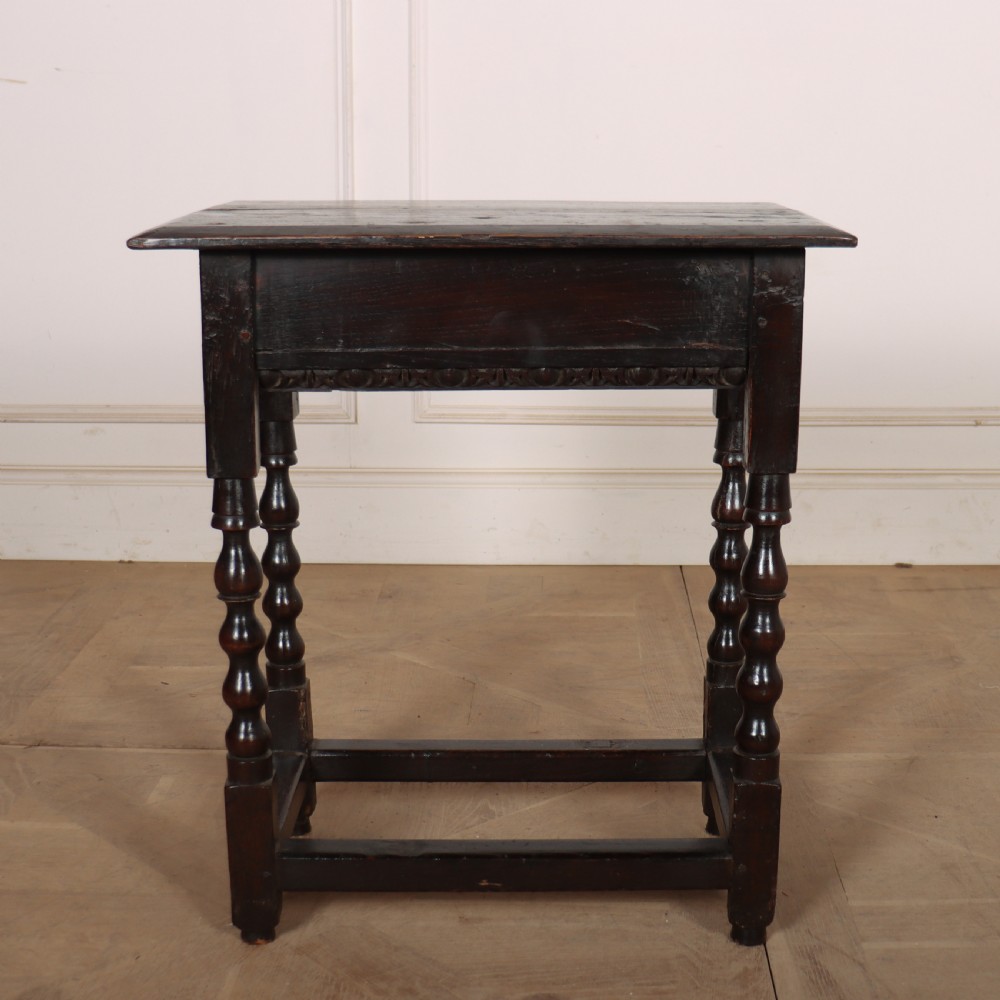 An 18th-century dark oak side table featuring turned legs, lower box stretchers, and a carved apron frieze. View VI