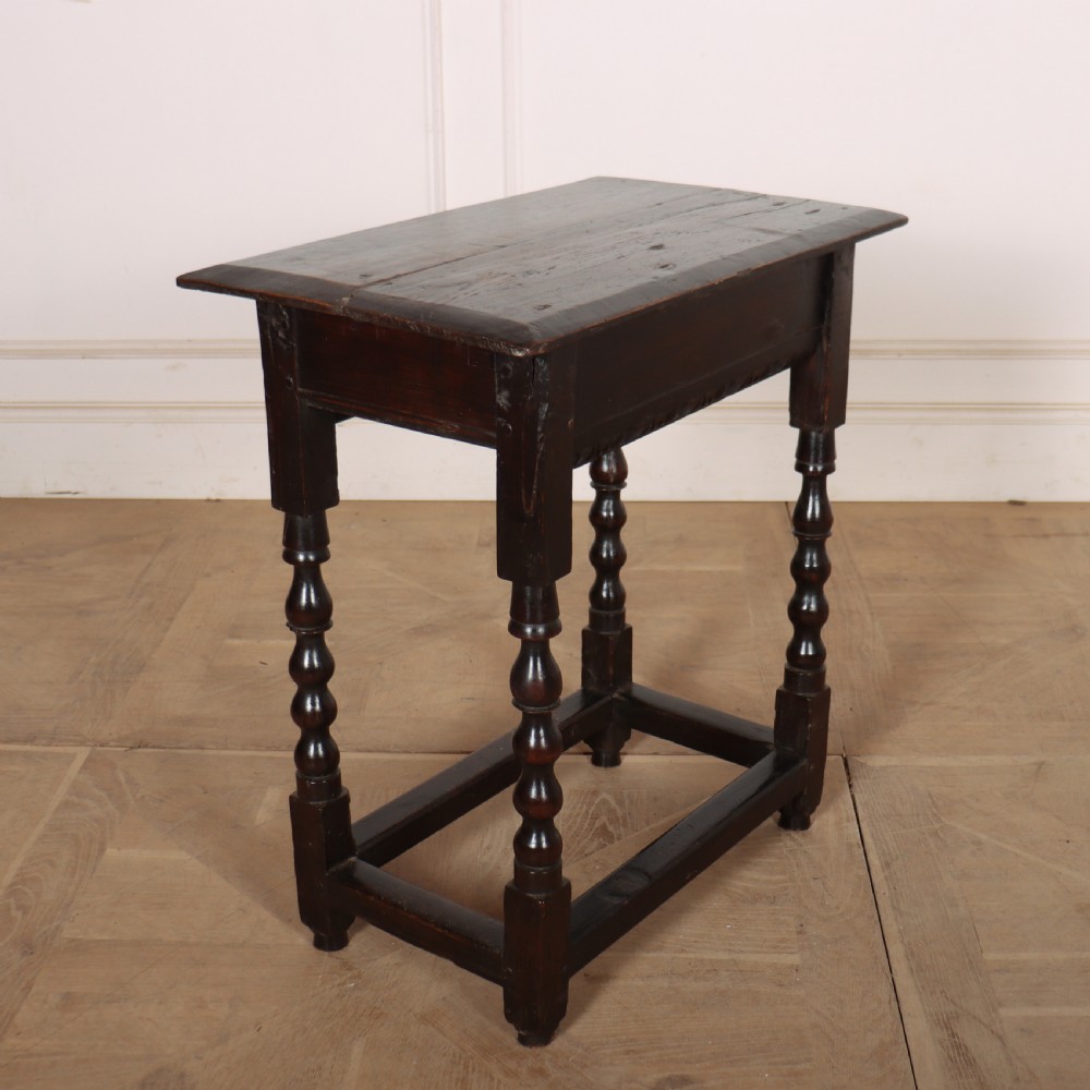 An 18th-century dark oak side table featuring turned legs, lower box stretchers, and a carved apron frieze. View VII