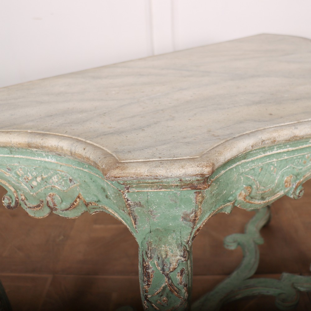 An Italian Rococo style console table featuring a distressed pale green painted finish, a serpentine marble top, intricate scroll carvings, and a contoured X-form stretcher. View VIII