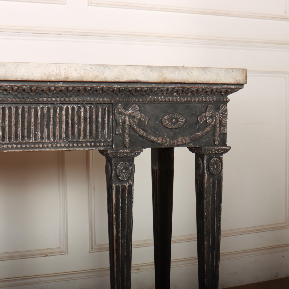 A Neoclassical dark grey painted console table with a marble top, featuring carved garland festoons and fluted tapered legs. View VI