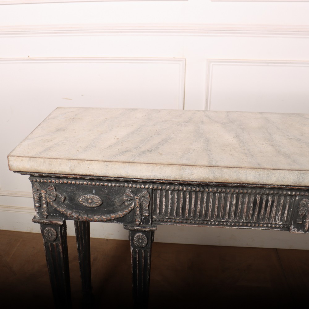 A Neoclassical dark grey painted console table with a marble top, featuring carved garland festoons and fluted tapered legs. View IX