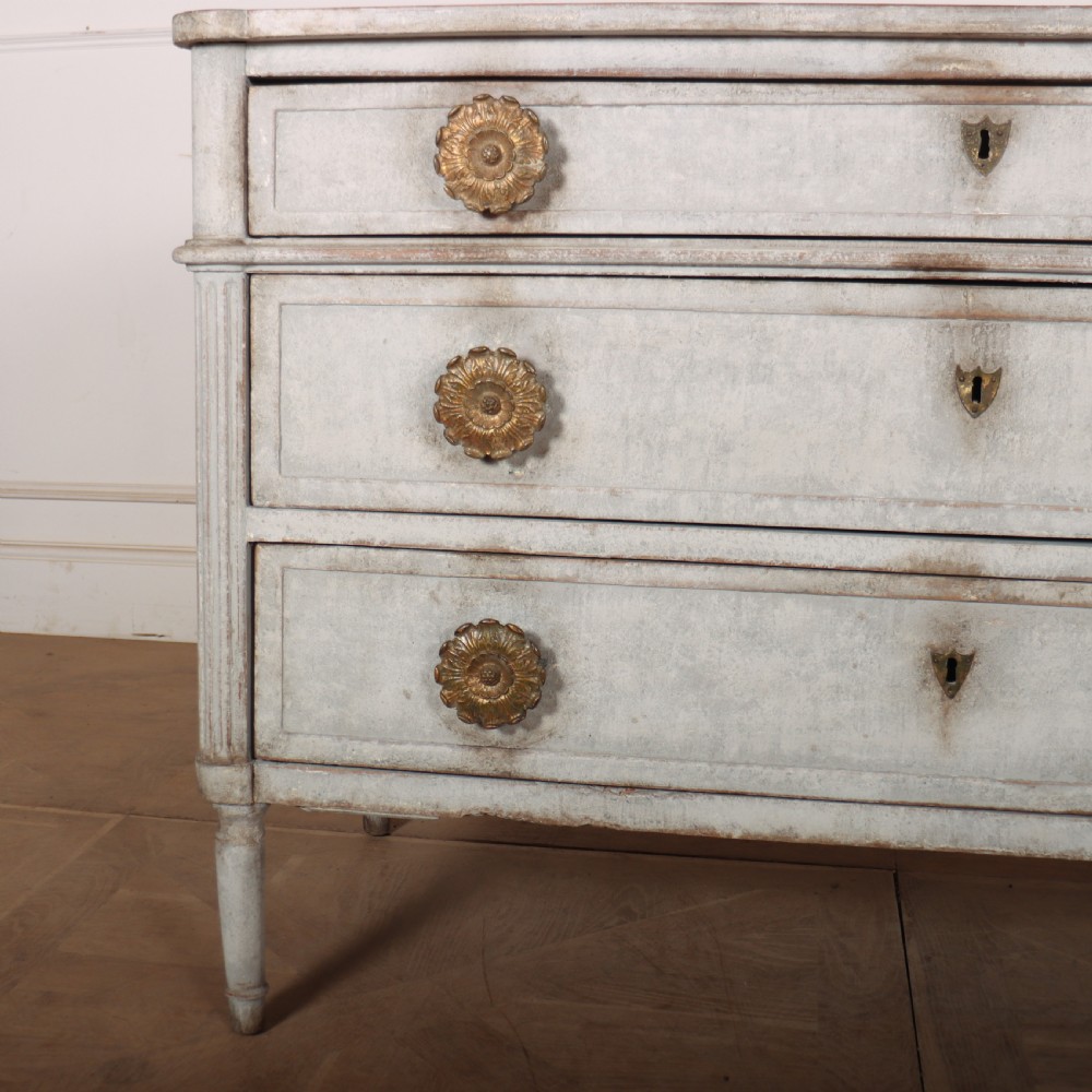 A Louis XVI style pale grey painted oak commode featuring three drawers with gilded rosette handles and fluted legs. View III