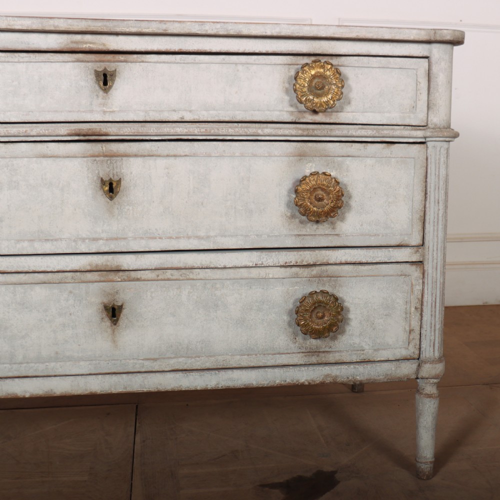 A Louis XVI style pale grey painted oak commode featuring three drawers with gilded rosette handles and fluted legs. View VII