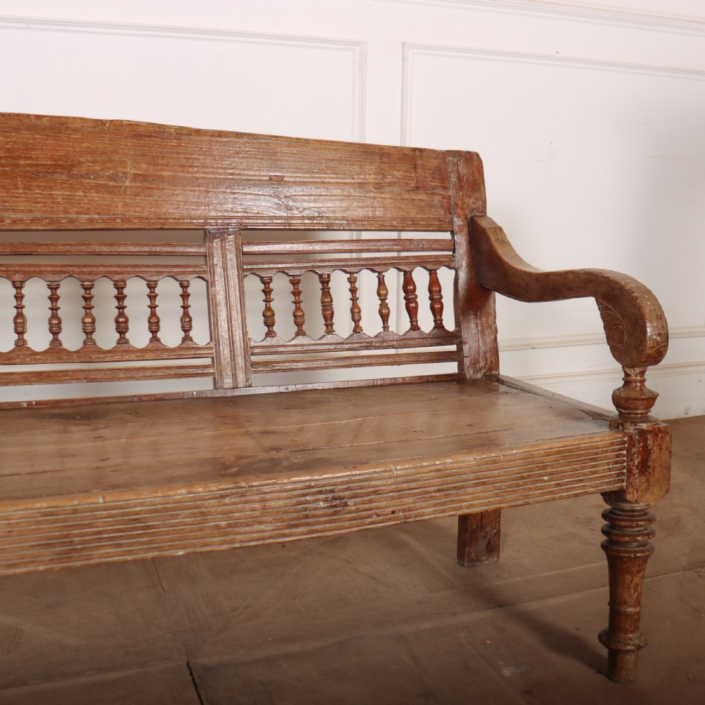 A 19th-century bleached chestnut wooden settle featuring a spindle-detailed backrest, curved armrests, and turned front legs. View II
