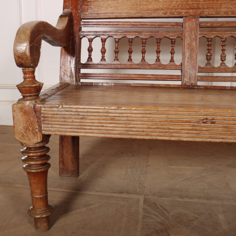 A 19th-century bleached chestnut wooden settle featuring a spindle-detailed backrest, curved armrests, and turned front legs. View VI