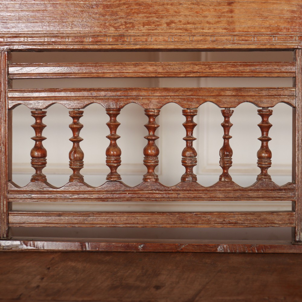 A 19th-century bleached chestnut wooden settle featuring a spindle-detailed backrest, curved armrests, and turned front legs. View IX