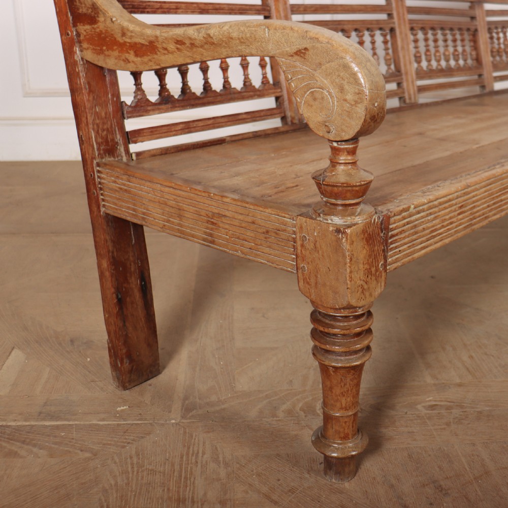 A 19th-century bleached chestnut wooden settle featuring a spindle-detailed backrest, curved armrests, and turned front legs. View XI