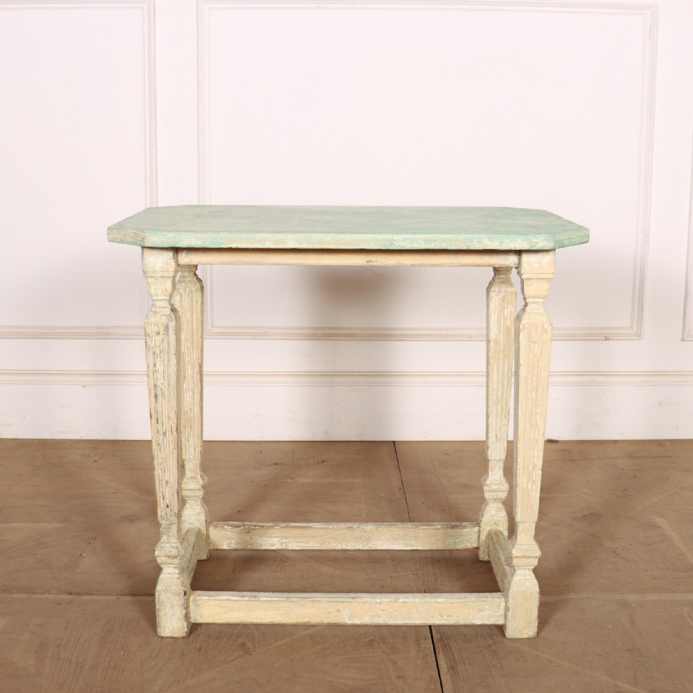 A small rectangular French wooden table with a pale green top, clipped corners, and cream distressed painted turned legs with a lower box stretcher.