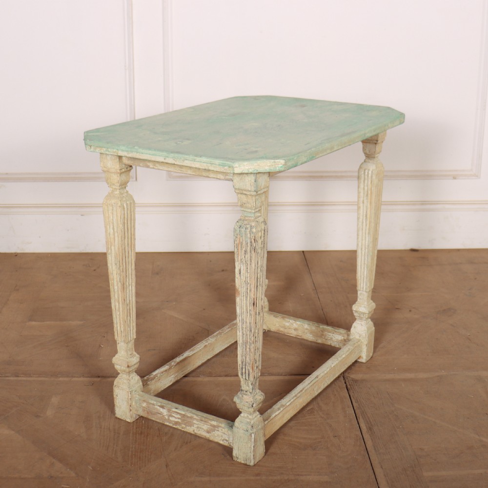 A small rectangular French wooden table with a pale green top, clipped corners, and cream distressed painted turned legs with a lower box stretcher. View V
