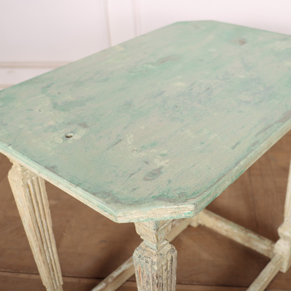 A small rectangular French wooden table with a pale green top, clipped corners, and cream distressed painted turned legs with a lower box stretcher. View VII