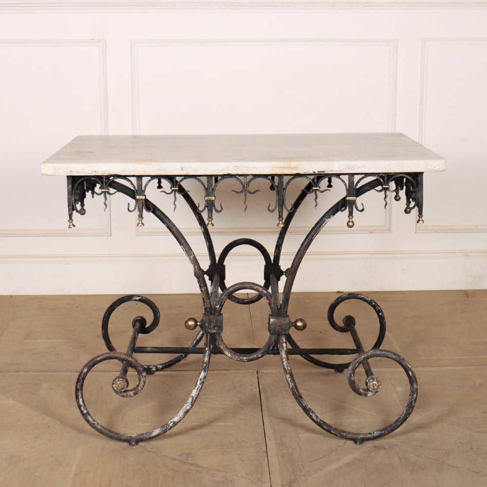 A 19th-century French patisserie table featuring a light marble top mounted on a dark wrought iron scrolled base with brass details.
