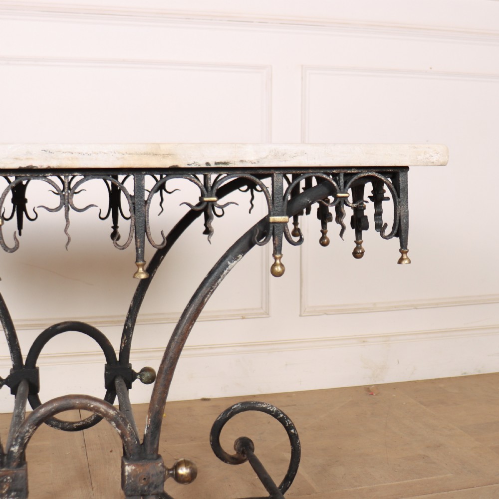 A 19th-century French patisserie table featuring a light marble top mounted on a dark wrought iron scrolled base with brass details. View V
