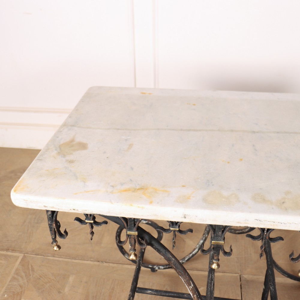 A 19th-century French patisserie table featuring a light marble top mounted on a dark wrought iron scrolled base with brass details. View VI