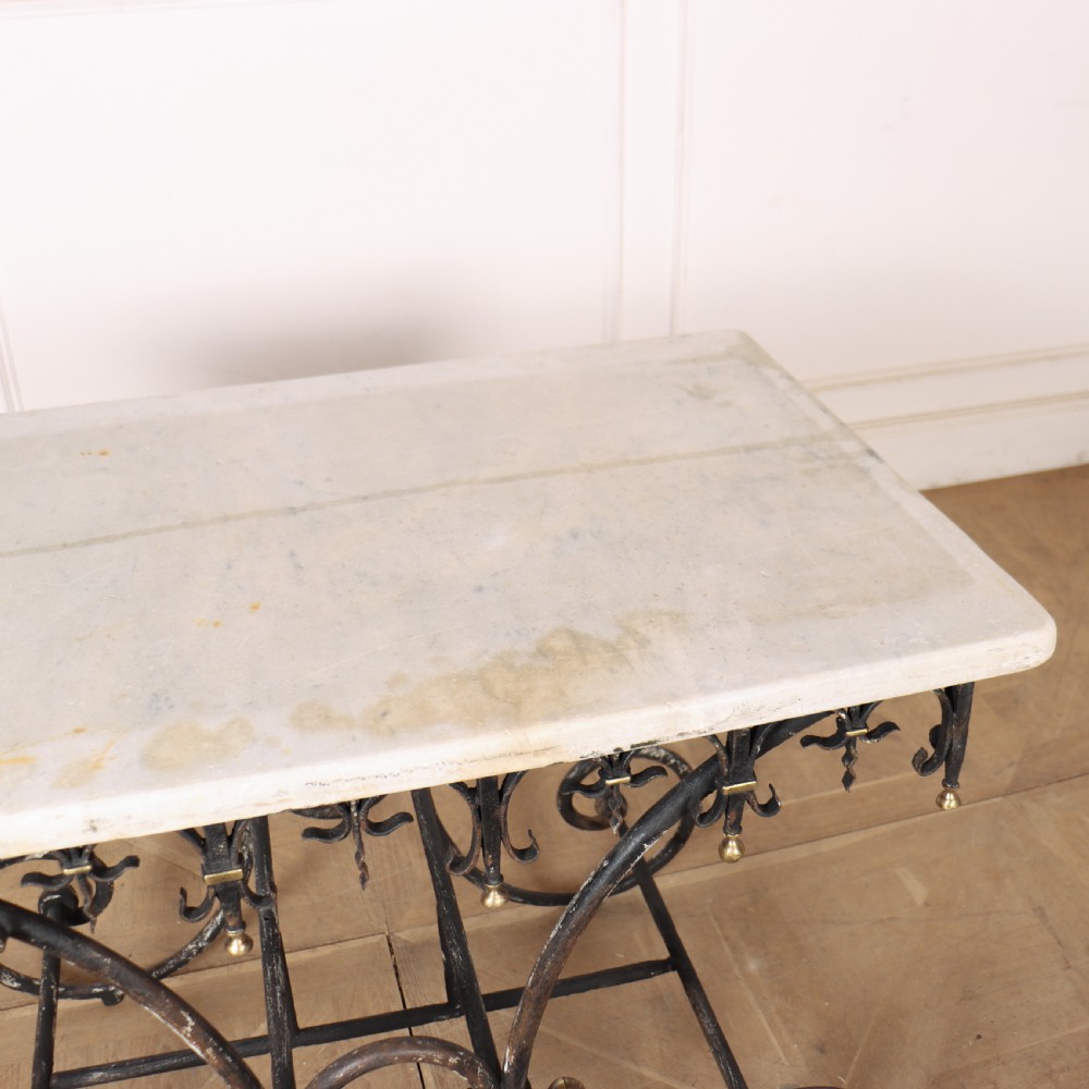 A 19th-century French patisserie table featuring a light marble top mounted on a dark wrought iron scrolled base with brass details. View X