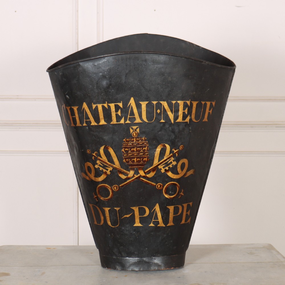 A tapered black painted sheet metal grape picking hotte with gold hand-painted lettering reading Chateauneuf du-Pape and a crest motif.