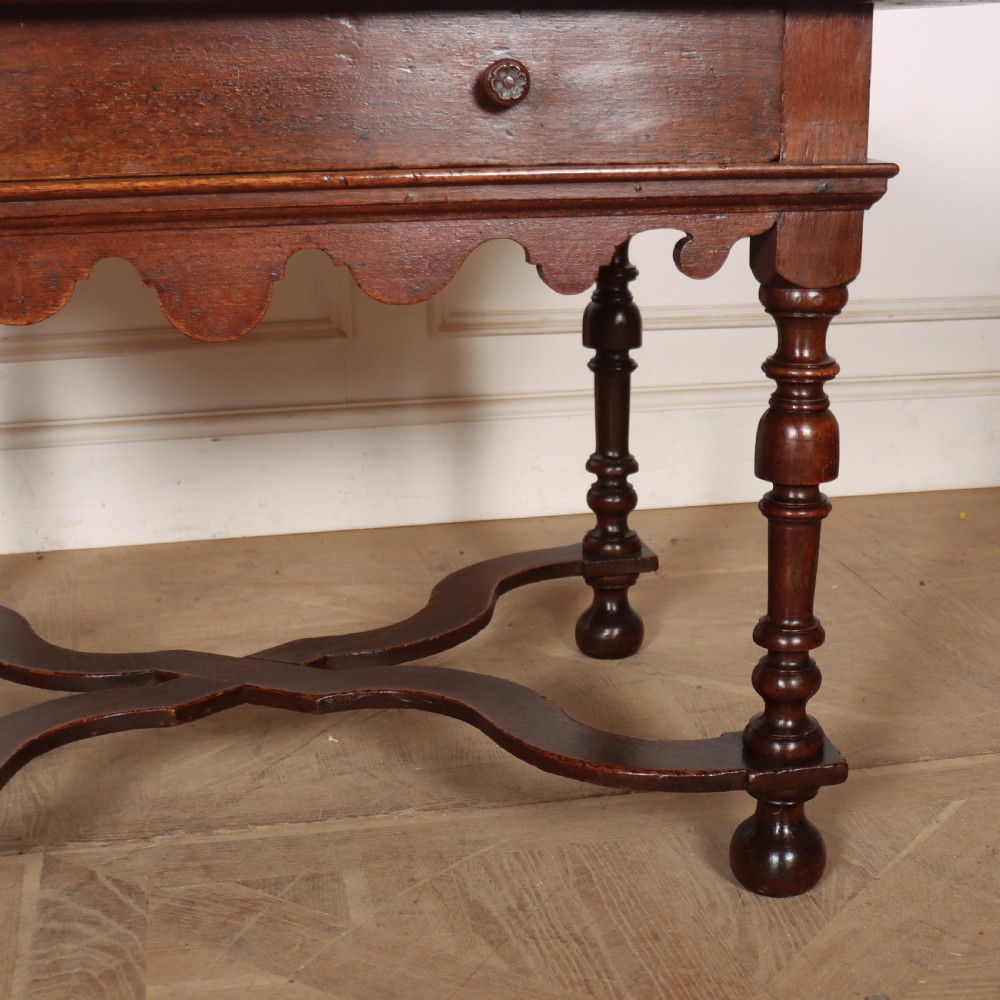 An 18th-century oak lamp table featuring a single drawer with brass knobs, a scalloped apron, turned legs, and an X-frame cross stretcher. View IV