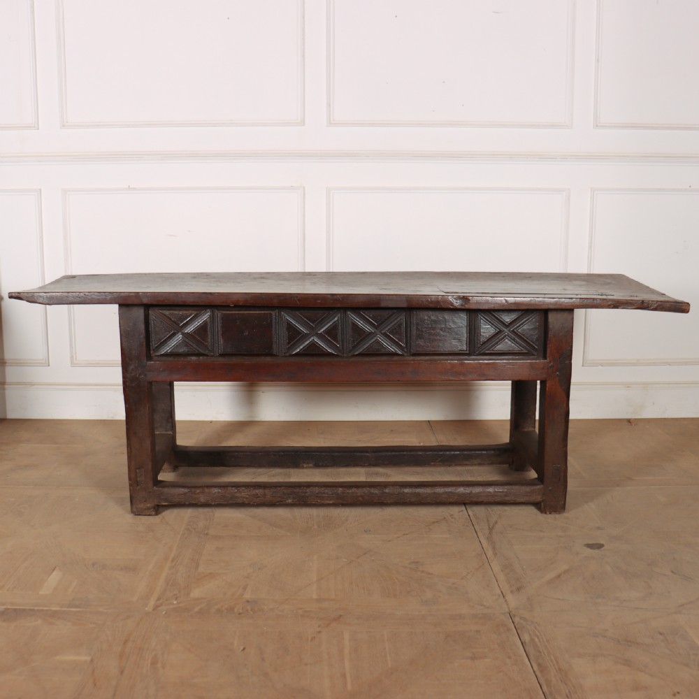 A 17th-century Spanish dark oak console table featuring a thick rectangular top over three geometric carved drawers, supported by sturdy legs with a perimeter stretcher. View XI