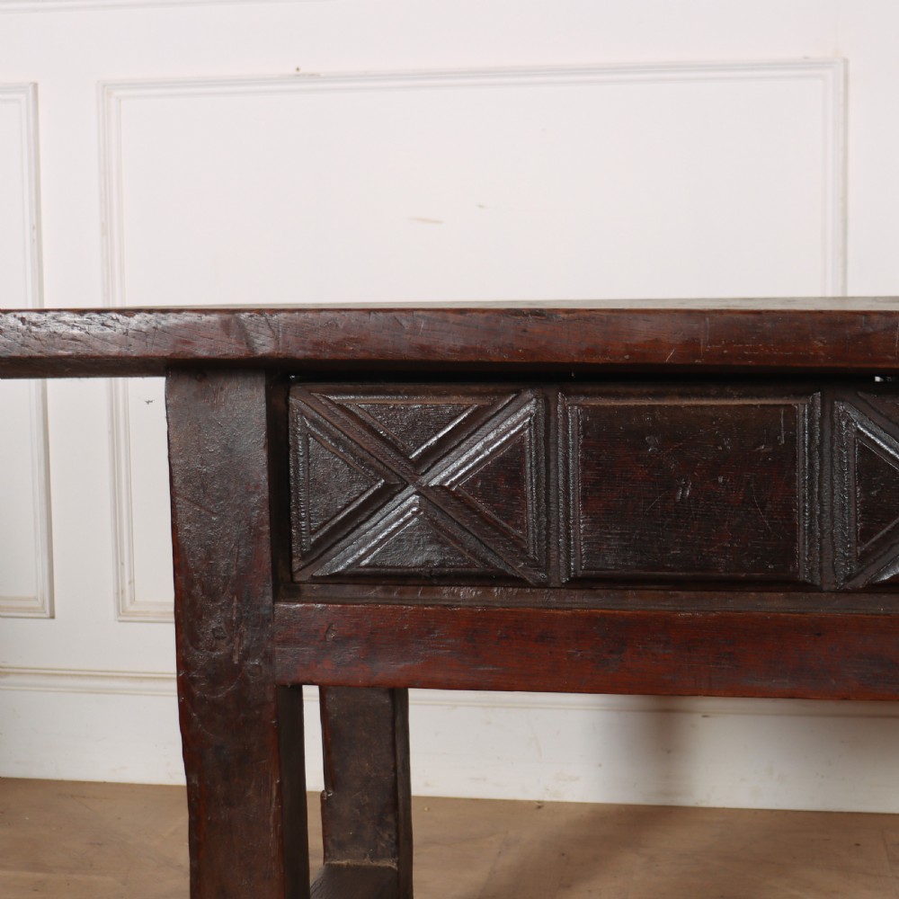 A 17th-century Spanish dark oak console table featuring a thick rectangular top over three geometric carved drawers, supported by sturdy legs with a perimeter stretcher. View XII