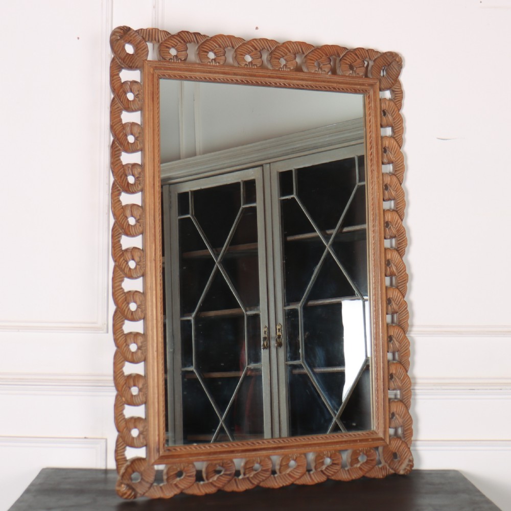 A rectangular wall mirror featuring an intricate hand-carved pine frame with an openwork twist pattern and warm wood finish.